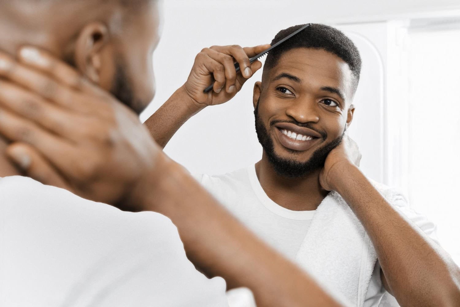 Ein Mann, der nach einer Afro-Haartransplantation sein volles Haar im Spiegel kämmt