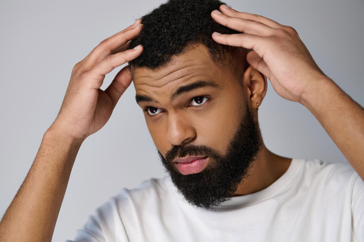  Ein Mann kontrolliert nach einer Afro-Haartransplantation seine Haare im Spiegel