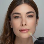 Schöne Frau mit einer Nadel am Mund bei der Lippenunterspritzung